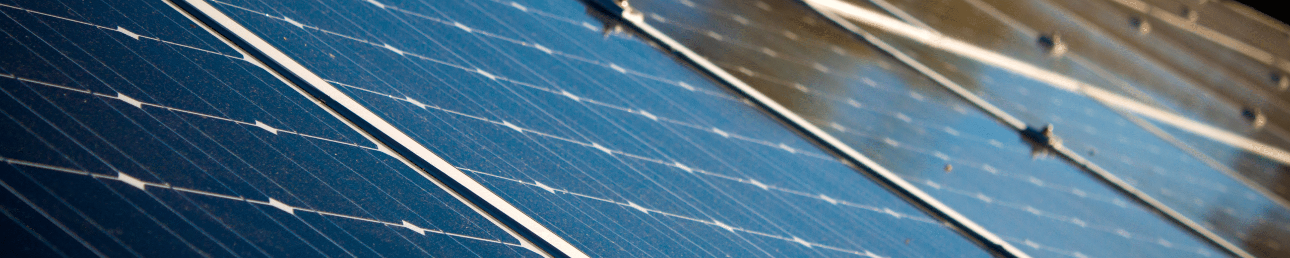 Close-up view of blue solar panels installed on a rooftop, showing reflective surfaces and metal framing.